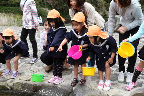 放流した鮎を見つけて指さす園児
