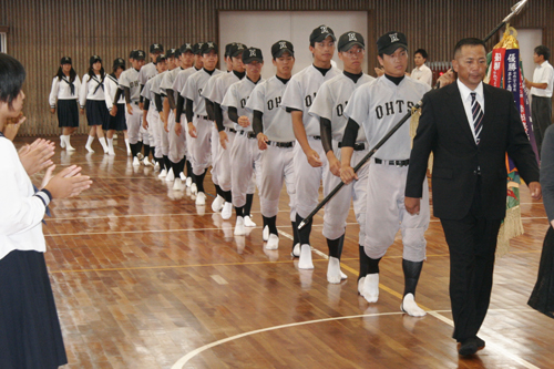 拍手の中、壮行式会場に入場する選手たち