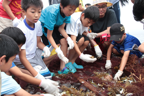 網にかかった魚に触れる子どもたち