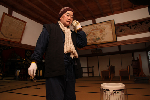 本堂内のストーブから発火した想定で、119番通報する岩田住職
