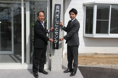 長門市しごとセンターの看板を掲げる大西市長と岡藤理事長