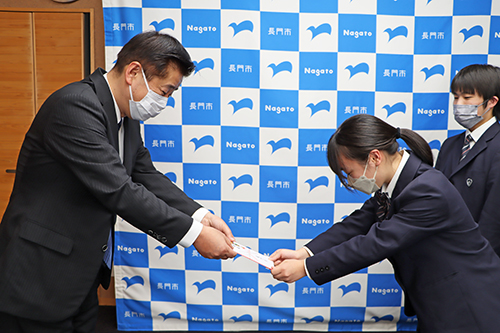 江原市長から激励費とTシャツが手渡された