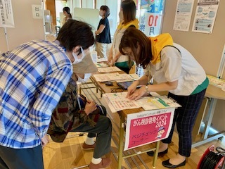 がん検診受診促進の啓発活動、乳がんモデルを使った触診の体験、明治安田によるベジチェックを実施