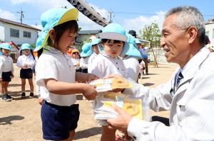 末永組合長が園児にお菓子を手渡す様子